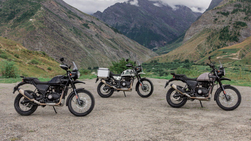 Drei Royal Enfield Himalayan 440 auf einer Gebirgsebene. Zu sehen sind die Modelle in Grau, Schwarz und Weiß im Seitenprofil