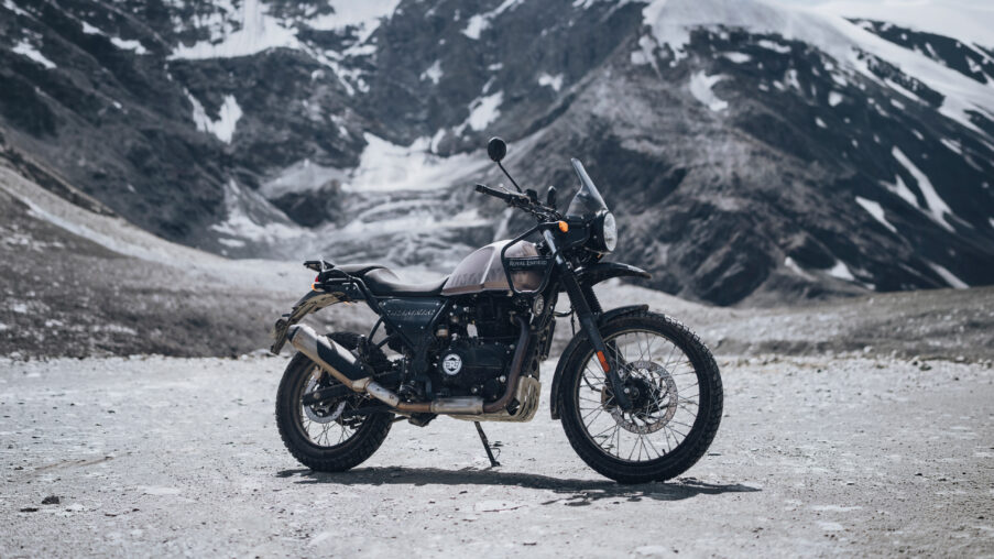 Zu sehen ist eine Royal Enfield Himalayan 440 im Seitenprofil auf einer Gebirgsebene. Im Hintergrund Gebirge des Himalaya.